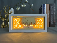 Boite lumineuse Bakugo MHA illuminée jaune orangé, yeux rouges féroces et croix d'explosion lumineuses posée sur bureau