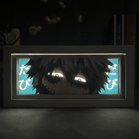 Boite lumineuse Dabi rétroéclairée en bleu cyan dans l'obscurité, regard sinistre My Hero Academia posée sur bureau