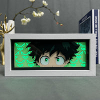 Boite lumineuse Deku MHA fond vert avec masques All Might lumineux, grands yeux verts expressifs cadre blanc horizontal