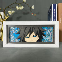 Boite lumineuse Giyu Tomioka Demon Slayer posée sur bureau, fond bleu avec vagues découpées en papier, cadre blanc