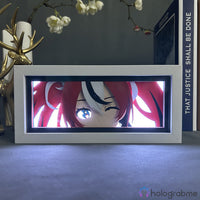 Boite lumineuse Hakos Baelz Hololive allumée lumière blanche, visage anime cheveux rouges et noirs expressif, posée bureau