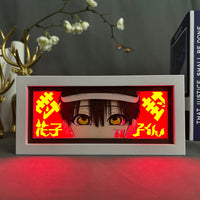 Boite lumineuse Hanako Kun éclairée rouge, yeux dorés lumineux et inscriptions japonaises sur fond écarlate brillant