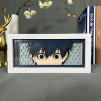 Boite lumineuse Isagi Yoichi Blue Lock posée sur bureau, fond bleu marine avec motifs hexagonaux découpés en papier