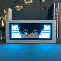 Boite lumineuse Isagi Yoichi éclairée en bleu, gros plan sur les yeux bleus intenses entourés de motifs hexagonaux lumineux