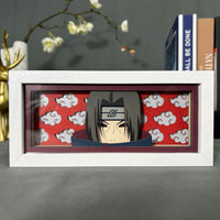 Boite lumineuse Itachi cadre blanc portrait ninja fond rouge nuages Akatsuki blancs, posée sur bureau