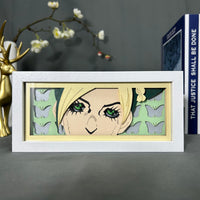 Boite lumineuse Jolyne Cujoh JoJo posée sur bureau, fond vert clair avec papillons découpés en papier, lumière douce