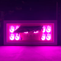 Boite lumineuse Jotaro JoJo illuminée en rose intense dans l'obscurité, mains luminescentes encadrant le visage du chasseur