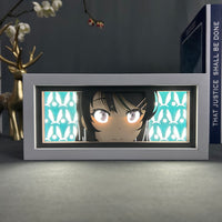 Boite lumineuse Mai Sakurajima allumée lumière bleue-verte, motifs lapins illuminés sur fond turquoise, posée sur table