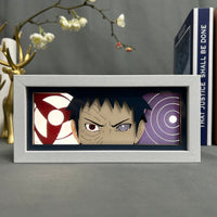 Boite lumineuse Obito Naruto fond sombre, deux yeux légendaires sharingan et rinnegan encadrés dans cadre blanc