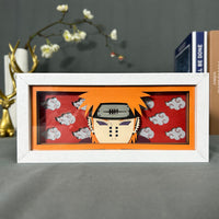 Boite lumineuse Pain Naruto fond rouge avec nuages Akatsuki, personnage avec piercings posée sur un bureau