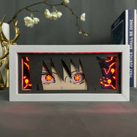 Boite lumineuse Sasuke rétroéclairée rouge, yeux sharingan brillants et motifs cursed seal en décoration gaming