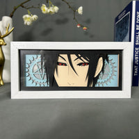 Boite lumineuse Sebastian Michaelis Black Butler posée sur bureau, fond noir avec engrenages et pentagramme découpés
