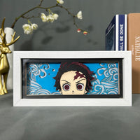 Boite lumineuse Tanjiro Kamado Demon Slayer posée sur bureau, fond bleu avec vagues d'eau découpées en papier