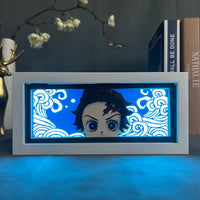 Boite lumineuse Tanjiro allumée en bleu LED, visage chibi du tueur de démons entouré de vagues lumineuses découpées