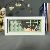 Boite lumineuse Yuno Black Clover posée sur bureau, fond vert clair avec trèfles à quatre feuilles découpés en papier