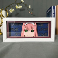 Boite lumineuse Zero Two Darling in the FranXX, visage aux cheveux roses et yeux verts sur fond bleu marine avec logos