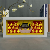Boite lumineuse Naruto cadre blanc portrait ninja cheveux blonds fond rouge tourbillons dorés, posée bureau