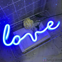Néon LED inscription love en cursive bleu électrique posé dans un panier métallique blanc