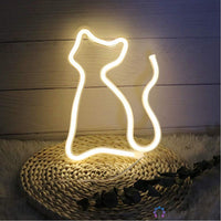 Néon LED chat silhouette blanc chaud posé sur natte en osier avec fleurs séchées, décoration zen