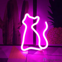 Néon LED chat silhouette rose fuchsia posé sur socle, décoration chambre avec ananas fond coloré
