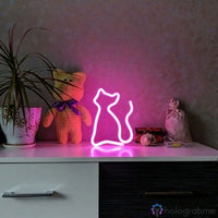 Néon LED chat silhouette rose posé sur commode blanche avec peluche et plante, décoration chambre