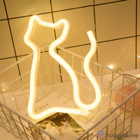 Néon LED chat silhouette blanc chaud posé dans panier grillage avec magazines, décoration bureau