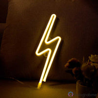Néon LED éclair jaune chaud posé sur un coussin de canapé, décoration salon chambre ambiance lumineuse dorée