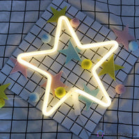 Néon LED étoile blanc chaud posé dans une grille murale avec pompon colorés et guirlande étoiles, chambre enfant