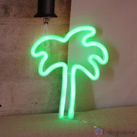 Néon LED palmier vert menthe posé sur canapé gris contre mur en briques, décoration intérieure cosy et tropicale