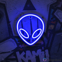 Néon LED alien entièrement bleu électrique avec yeux en amande accroché sur mur tagué, décoration murale chambre ado