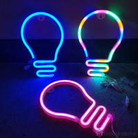 Trois néons LED ampoule bleu, orange et rose posés au sol dans l'obscurité, choix de couleurs disponibles