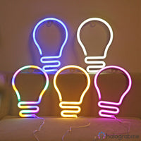 Cinq néons LED ampoule en couleurs variées bleu, blanc, vert, orange, rose alignés sur un meuble