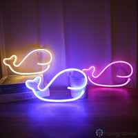 Trois néons LED baleine posés sur une étagère, coloris jaune chaud bleu et rose, décoration chambre enfant
