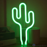 Néon LED cactus vert posé sur un bureau à côté de livres et d'un pot, décoration chambre cosy