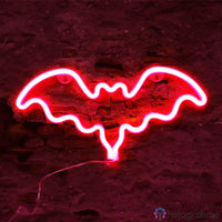 Néon LED chauve-souris rouge vif aux ailes déployées accroché sur mur de briques, décoration Halloween
