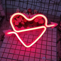 Néon LED cœur cupidon rouge avec flèche posé sur carrelage blanc près d'une tour Eiffel miniature