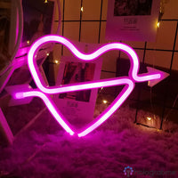 Néon LED cœur cupidon rose fuchsia avec flèche, posé sur tapis blanc moelleux, décoration chambre