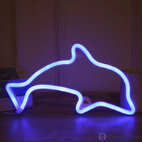 Néon LED dauphin bleu lumineux posé sur le sol contre un mur blanc, décoration chambre