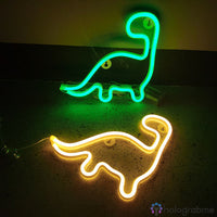 Deux néons LED dinosaure coloris vert et jaune chaud posés côte à côte sur une surface sombre, décoration gaming