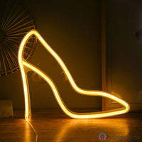 Néon LED escarpin talon haut jaune doré posé sur un parquet, décoration chambre féminine tendance