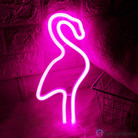 Néon LED flamant rose fuchsia intense posé contre un mur de briques, décoration chambre tendance