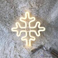Néon LED flocon de neige blanc chaud posé sur un tapis moelleux gris, décoration de Noël