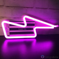 Néon LED éclair rose violet posé sur surface brillante avec boîte cadeau rayée, décoration moderne