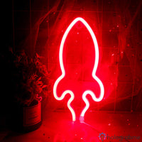 Néon LED fusée rouge vif posé devant un voilage étoilé, décoration chambre enfant ou ado ambiance cosmos
