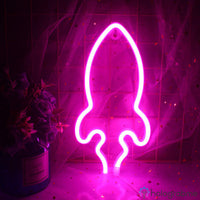 Néon LED fusée rose vif accroché sur un mur carrelé avec plante en arrière-plan, décoration chambre ado