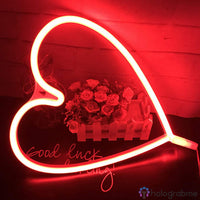 Néon LED grand cœur rouge lumineux posé près d'un bouquet de roses, ambiance romantique