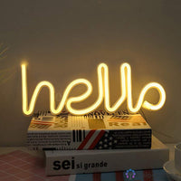 Néon LED hello blanc chaud en lettres cursives posé sur des livres empilés, décoration bureau ou chambre
