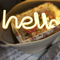 Néon LED hello blanc chaud en script allongé posé dans un panier fleuri, décoration chambre cosy bohème