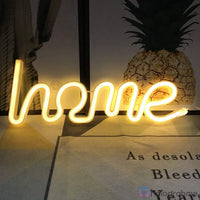 Néon LED home blanc chaud en script posé à plat avec un ananas en décoration, ambiance tropicale et lumineuse