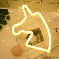 Néon LED licorne blanc chaud posé dans une grille décorative avec guirlande lumineuse, ambiance chambre cosy